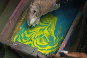 A student moves the spray paint around with a toothpick 
to make a unique design in the solution made of water 
and spray paint. Students then dip their Styrofoam 
project into the container to color it.