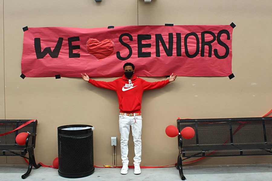 Senior Trevaughn Currington stands beneath a senior banner on Class Color Day during Spirit Week in March.