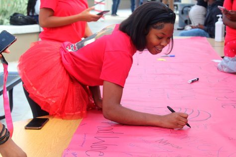 Senior Sara Walker signs the senior banner during Class Color Day Oct. 6.  