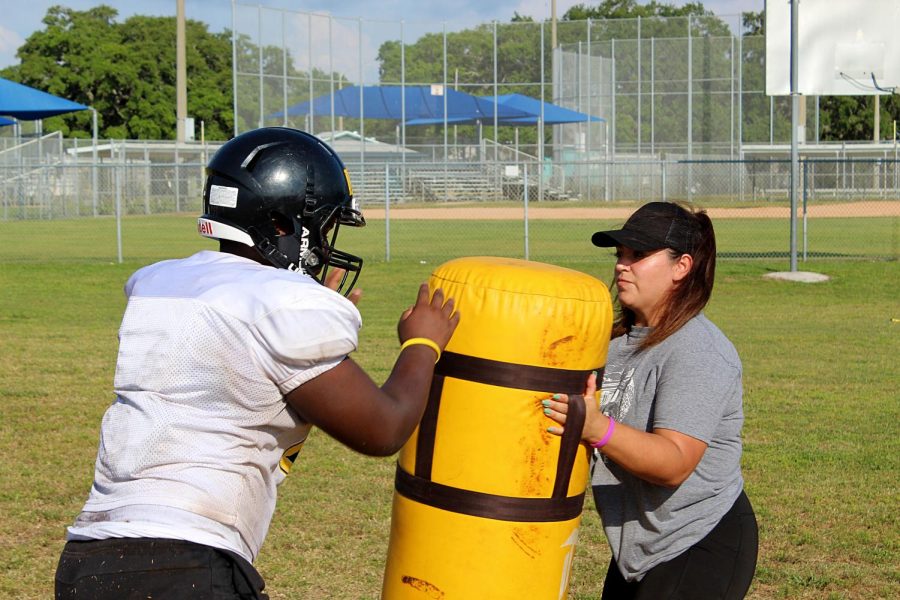 Coach Melia Garcia works with a player from the offensive line on a blocking drill in May on the Lakewood High School practice field. 