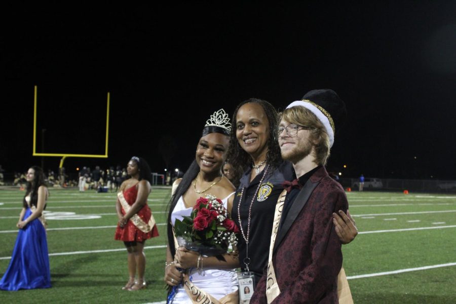 From left, Homecoming queen Torriell Norwood, principal Erin Savage and Homecoming king Dante Giuffre pose on the field on Oct. 8 during halftime. The king and the queen will attend the Homecoming dance.