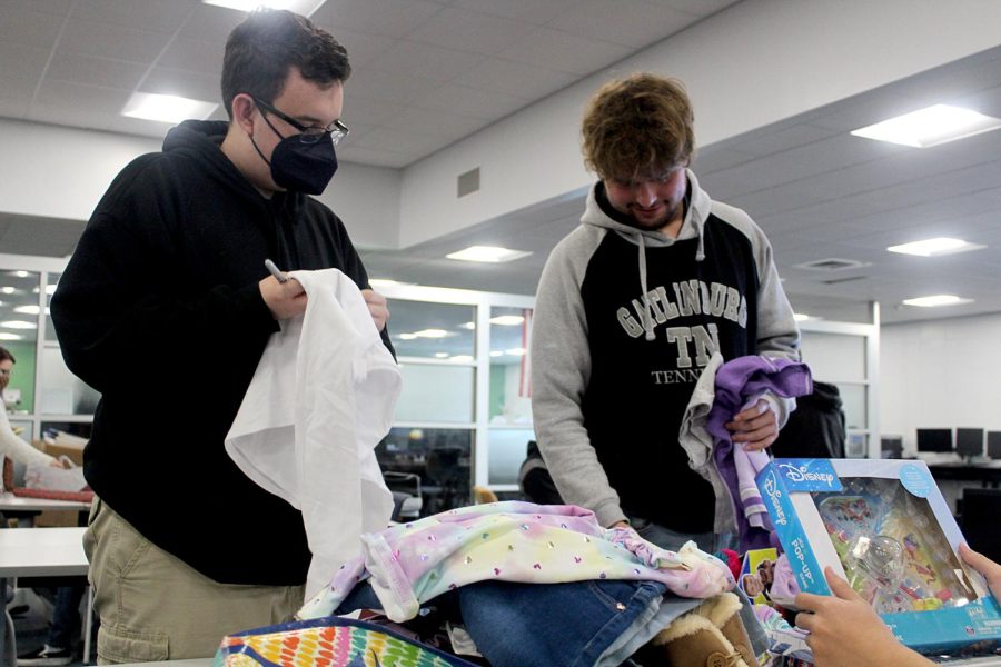 Juniors Wayne Worth and Ashton Ashton check presents for price tags in the media center on Dec. 7. After any price tags are removed, presents are taken to be wrapped as part of the Giving Tree innitiative. 