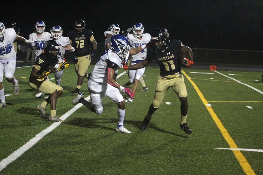 Senior Diezel Spann holds off an East Lake High School player while trying to run the ball at Lakewood High School on Oct. 11. The Spartans won 36-6. 