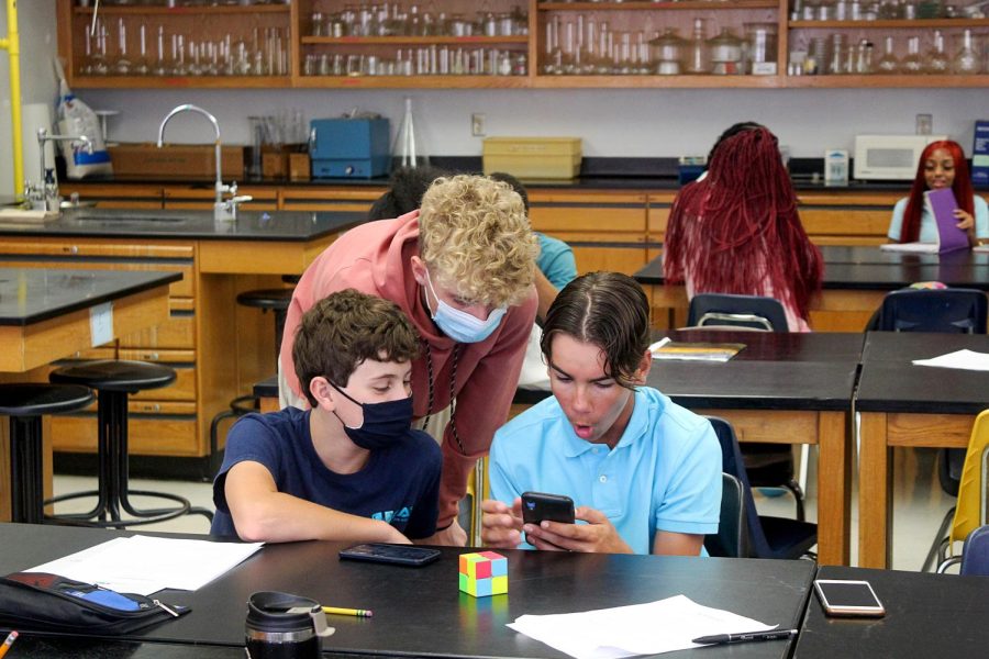 Sophomores Tyler Hollan, Nick Boddle and Brady Warner look at pictures on their phone as their fifth- period class comes to an end on Aug. 11.