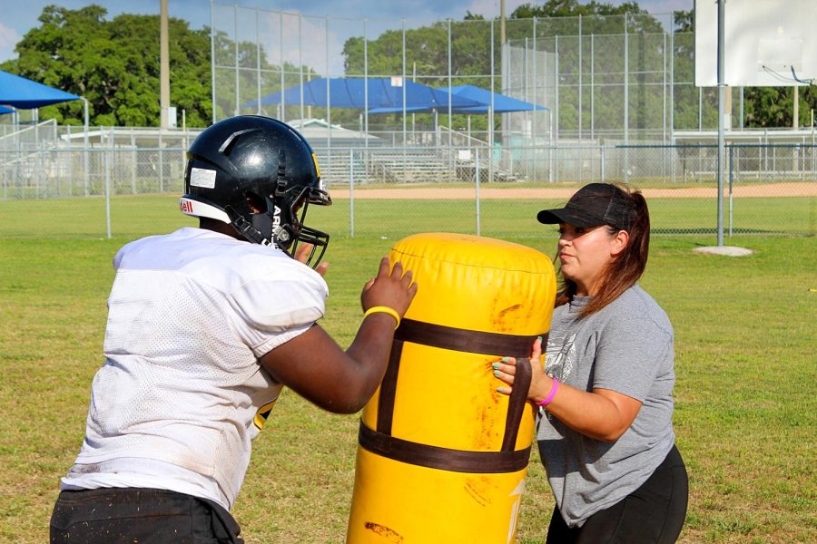 Assistant coach Melia Garcia, the first woman to coach on the sidelines of a Pinellas football game, works with a player from the offensive line in May 2021.