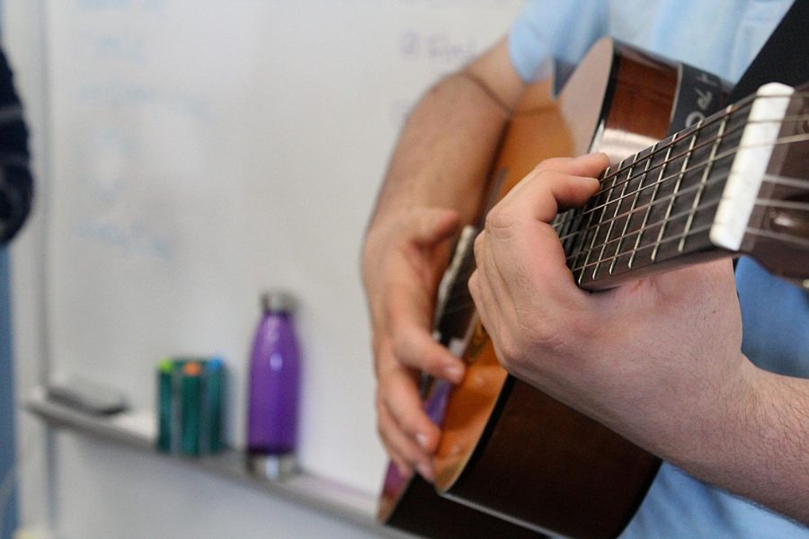 Junior Steven Chisari practices with his guitar in the band room on March 9. 