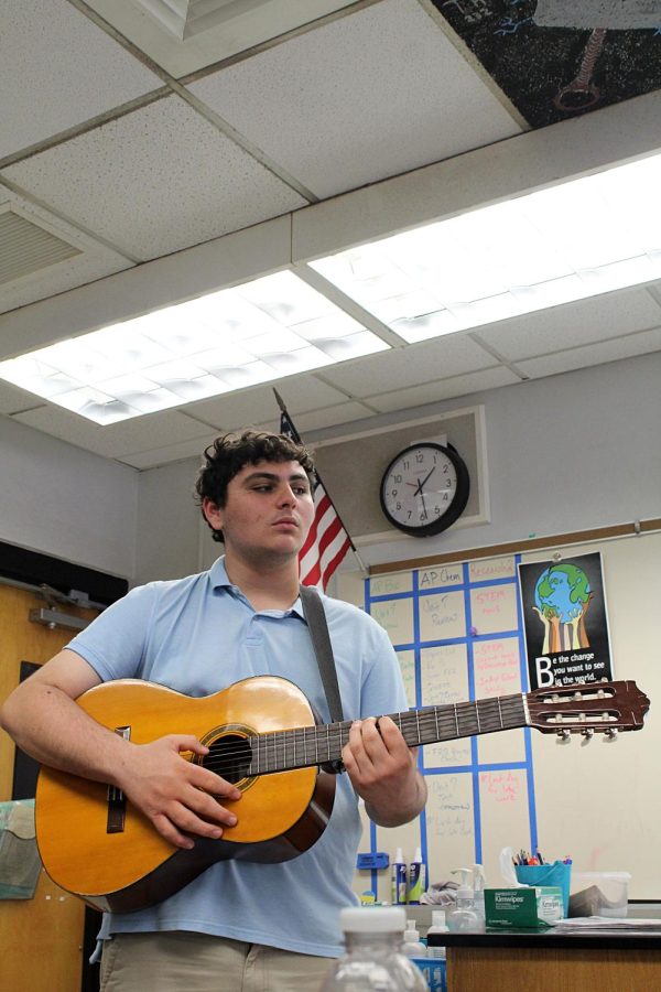 Junior Steven Chisari strums his guitar in front of science teachers Jennifer Pacowta seventh period class on March 9. 