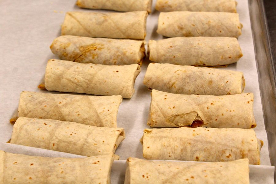 Burritos are lined up on a cooking tray in the back of the cafeteria in the prepping area on April 5. The burritos are placed on the tray so it can be prepared to get wrapped up and served out during lunchtime.