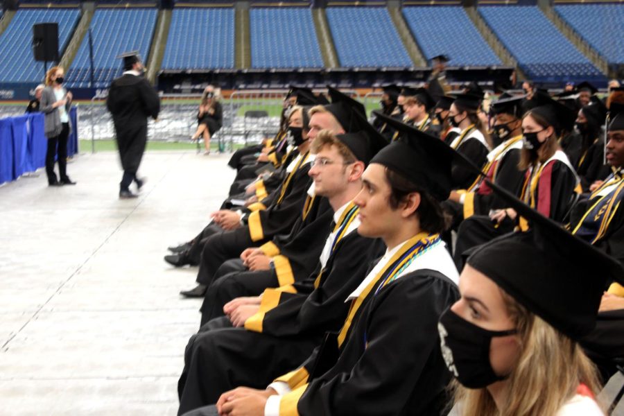 Seniors from last year's Class of 2021, dressed in their caps and gowns, listen to a speaker during the ceremony at Tropicana Field.
