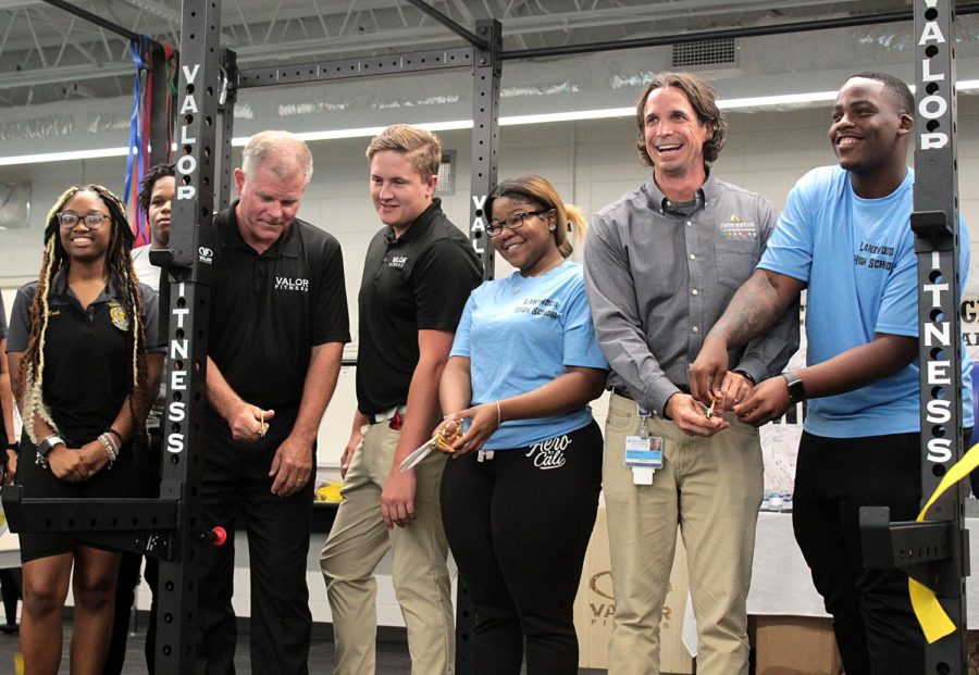 At center Lakewood alumna Diamond Brown cuts the ribbon for the new ALMA fitness center in room 406 on Aug. 8. She is flanked by representatives for Valor Fitness and Johns Hopkins, partners of the ALMA program.