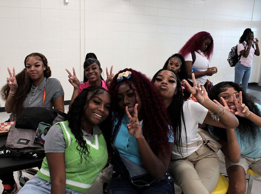 From left juniors Marquia Bush and Janae Battle pose in the Lakewood cafeteria surrounded by friends on Aug. 10.