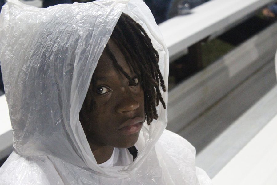 Freshman Jameel Joseph sits in the stands while wearing a poncho during the game against Northeast High School. 
