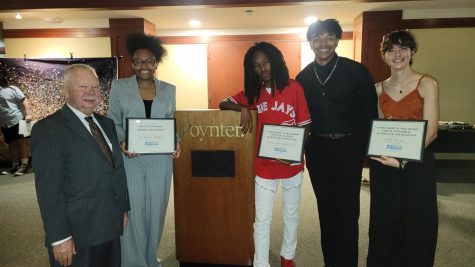 Kevin Mort (left), seniors DeMarria Raiford and James Cruickshank, photojournalism teacher Jordan Pompey, and senior Bella Croteau stand at the podium at the Poynter Institute on May 2. The three seniors pictured all won scholarships to help with college tuitions. 