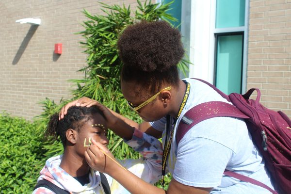 A student gets his face painted during lunchtime on black and gold day. Facepaint is a common way for students to show school spirit.