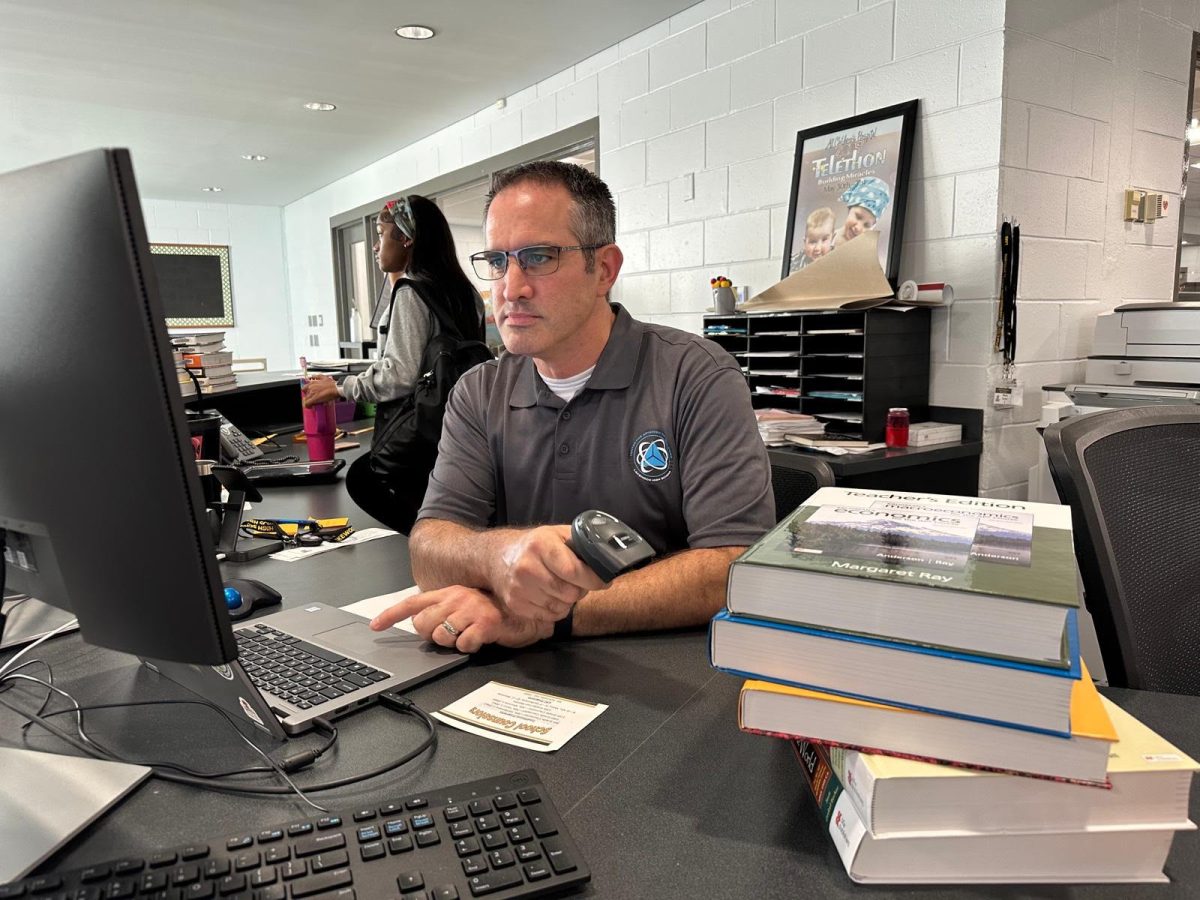 Media Center Specialist David Russo works diligently in the Library checking out textbooks for students. 