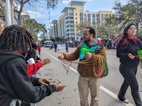 Kids reach out to grab as many plastic beaded necklaces as possible from those marching at the 'Dream Big' parade. For over 38 years, our community has celebrated MLK's legacy, making this parade the longest running MLK parade in history.