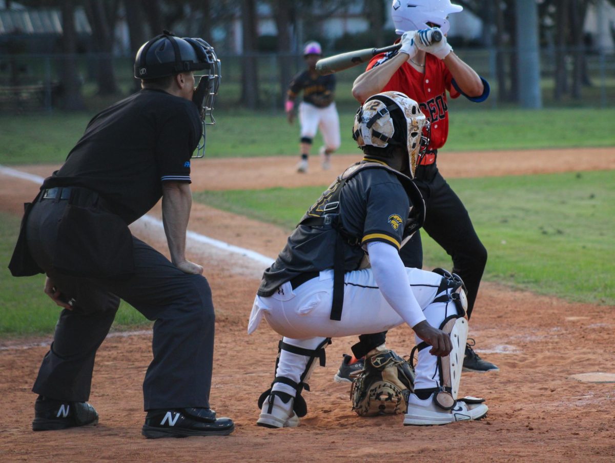 Senior Mikal Morris squats behind the Osceola player and catches the ball that the pitcher threw on Feb. 18th at Lake Vista Park.