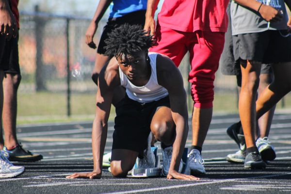 Sophomore Akierio Brumadge positions himself on a starting block, ready for a sprint. 