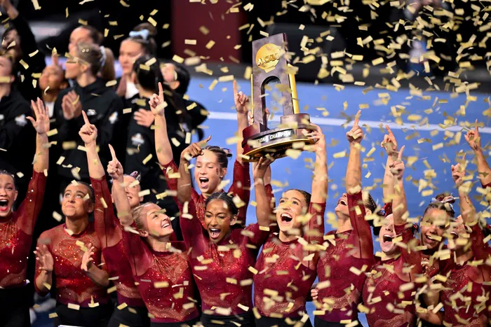 The Oklahoma gymnastics team celebrates with the trophy after the Sooners win the NCAA Championships. 