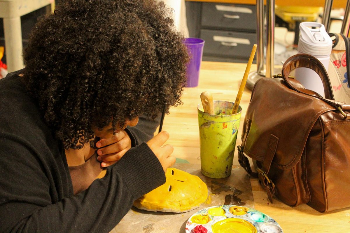 A student paints a clay pie sculpture at Art Club after school.