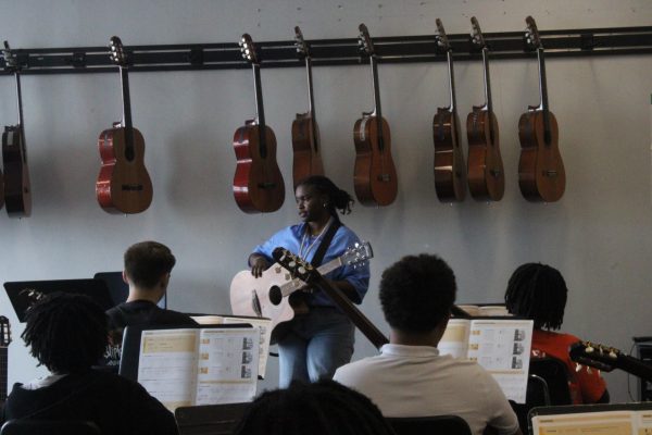 Mrs. Ash-Peterson holding the guitar and teaching different strings on August 22, 2025 in the guitar room. "I love teaching students about guitar," said Mrs. Ash-Peterson.