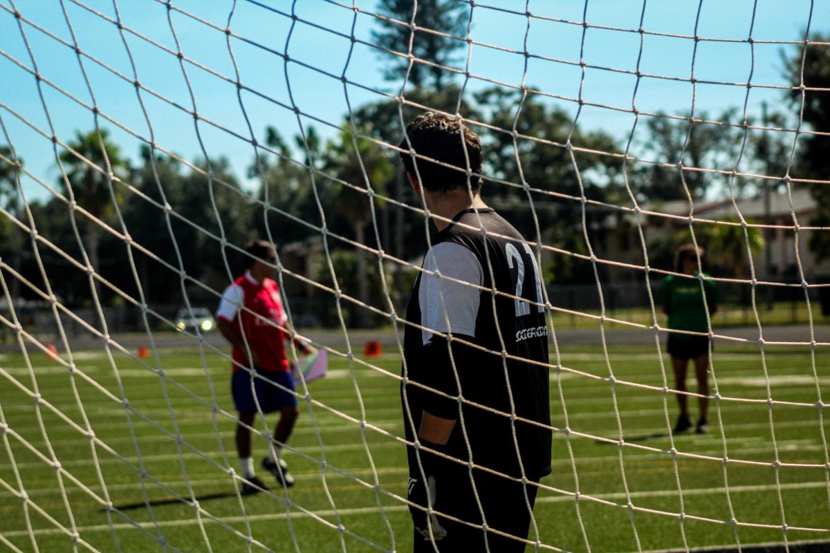 Sophomore Daniil Kelmakhter stands in the goal watching Coach Mills explain the drill to players.