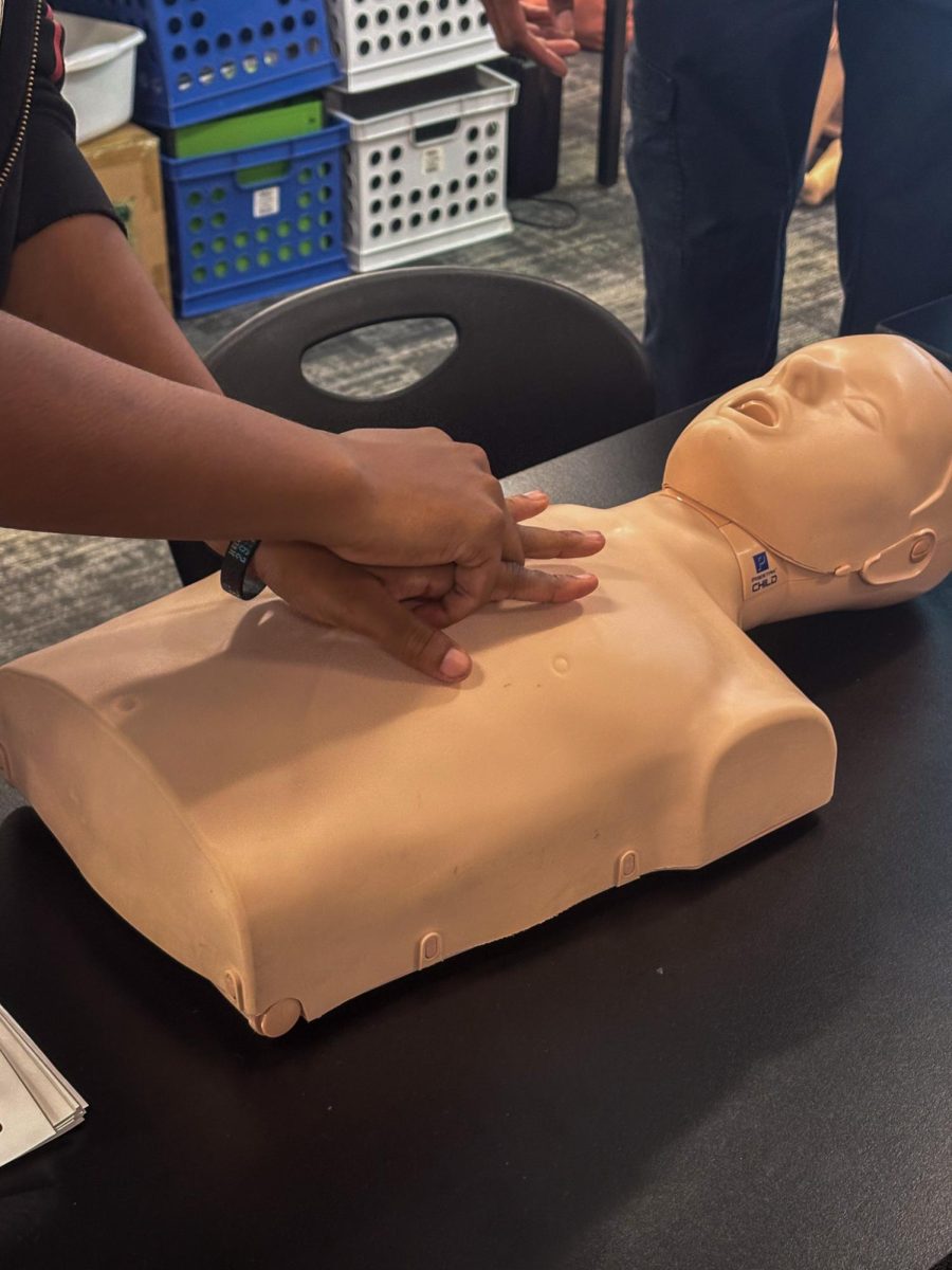 A student practicing performing CPR on a mannequin, aiming for two green lights on its chest in Ms. Milner's classroom at Lakewood High School on Jan 23.